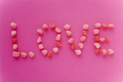 Schriftzug 'Love' aus kleinen rosa Zuckerbonbons