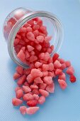 Kleine rosa Zuckerbonbons fallen aus einem Glas