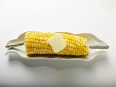 Corn on the cob with knob of butter in white dish