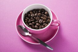 Kaffeebohnen in rosa Kaffeetasse mit Löffel