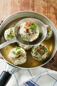Clear broth with bacon dumplings in frying pan & on ladle