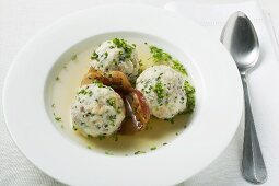 Clear broth with bacon dumplings in soup plate
