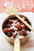 Sugared raspberries in a pan, empty jam jars