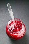 Raspberry jam in jar with spoon (overhead view)