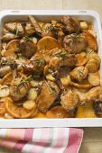 Chicken pieces with oranges and rosemary on baking tray