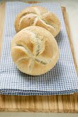 Two bread rolls on blue and white checked cloth