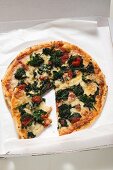 Spinach, tomato and cheese pizza in pizza box