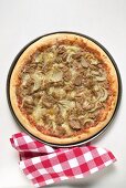 Thunfisch-Zwiebel-Pizza, daneben karierte Serviette