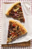 Zwei Stücke Pizza mit Hackfleisch und Zwiebeln auf Papier