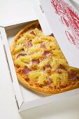 Hawaiian pizza with ham and pineapple in pizza box