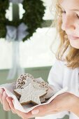 Blond girl holding assorted gingerbread biscuits on napkin