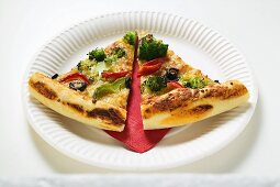 Two slices of American-style vegetable pizza on paper plate