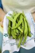 Hands holding green beans on cloth