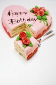 Pink heart-shaped birthday cake with piece on server