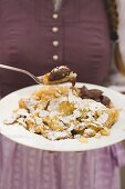 Frau hält Teller mit Kaiserschmarrn mit Zwetschgenröster