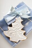Gingerbread fir tree with white icing beside gift