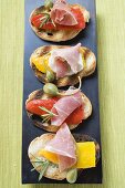 Crostini with raw ham, peppers and giant capers