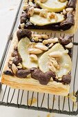 Two pieces of pear & chocolate tart with almonds on cake rack