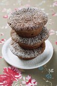 Three chocolate buns with icing sugar, in a pile
