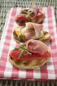 Several crostini with raw ham, peppers and giant capers
