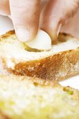 Filling baguette slice with clove of garlic