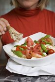 Frau isst Brot zu Tomaten mit Mozzarella und Basilikum