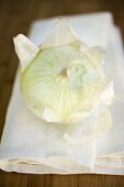 Onion, partly peeled, on linen cloth
