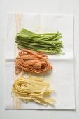 Home-made coloured ribbon pasta on tea towel