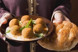 Woman serving falafel (chick-pea balls) with flatbread