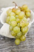 Green grapes on cloth in white bowl