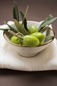 Olive sprig with green olives in bowl on linen cloth