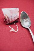 Rose hip tea bag, spoon beside it