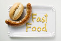 Bratwurst mit Brötchen und Senf (Schriftzug Fast Food)