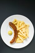 Sausage with chips and mustard on plate