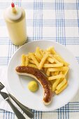 Sausage with chips and mustard on plate in restaurant