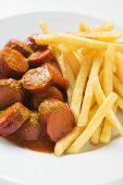 Currywurst mit Ketchup und Pommes frites auf Teller