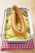 Frankfurters with potato salad in aluminium container