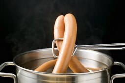 Lifting frankfurters out of hot water with tongs