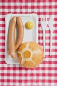 Frankfurters with mustard and bread roll on paper plate