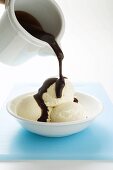 Pouring chocolate sauce over vanilla ice cream