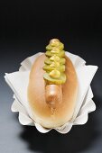 Hot Dog mit Essiggurken und Senf auf Pappteller