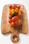 Various types of tomatoes in plastic tray on chopping board