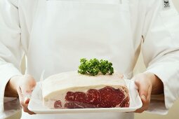 Person holding sirloin steak on tray