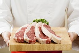 Chef holding sirloin steaks on chopping board