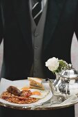 Butler serviert englisches Frühstück auf Tablett