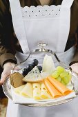 Waitress serving a cheese platter with grapes and crackers