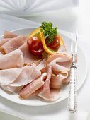 Platter of ham with cherry tomatoes, orange and parsley