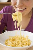 Young woman eating ribbon pasta