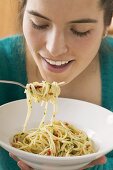 Young woman eating spaghetti with chillies