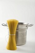 Spaghetti in front of perforated basket from pasta pan